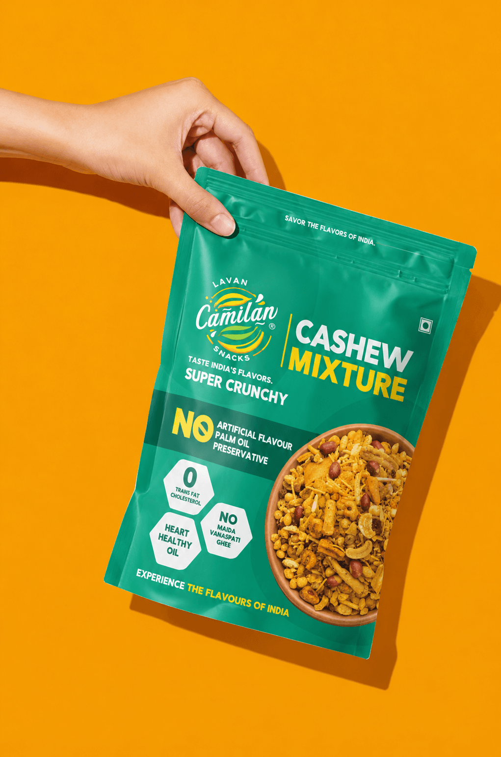 Hand holding a Cashew Mixture pouch against an orange background